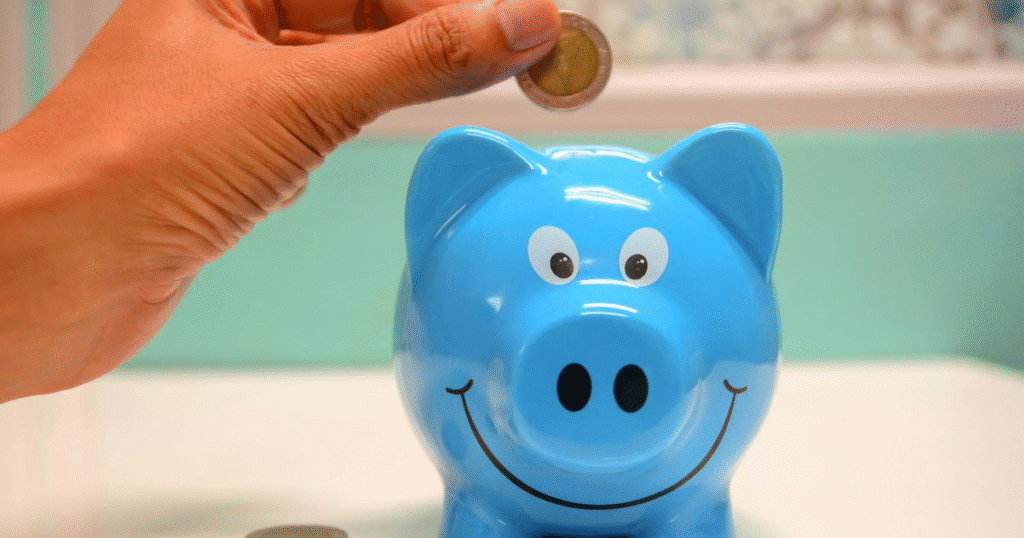 a picture showing budgeting tips for beginners: a hand placing a coin into a blue piggy bank.