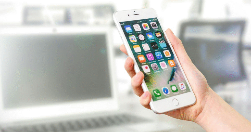 A picture showing a person holding a phone displaying apps, emphasising the importance of using a budgeting app.