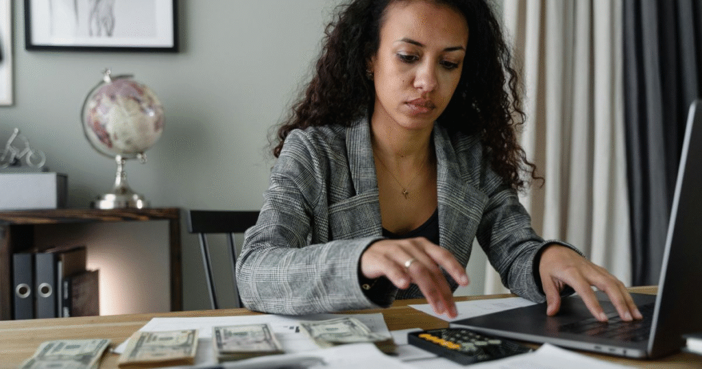 A picture showing a woman using a laptop and a calculator to track financial expenses: budgeting tips for beginners.