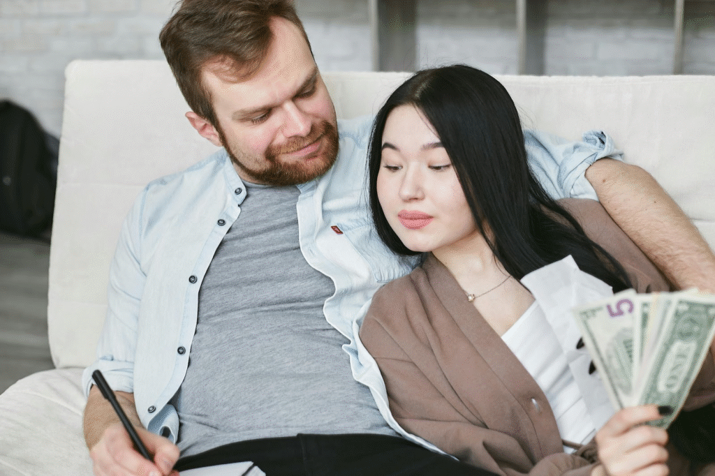 A couple sitting together on a sofa, discussing their finances and practicing budgeting as a couple. 