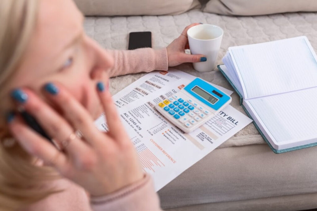 A beautiful young Albino woman sitting with a calculator and bills, doing paperwork.