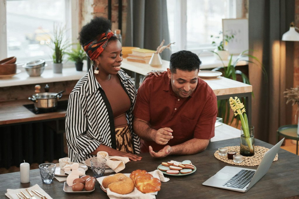A happy couple eating and looking at a laptop, showing harmony as a result of split finances in marriage.