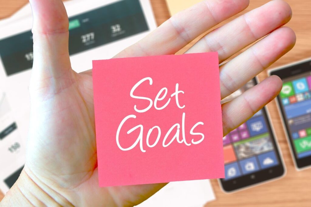 An Image showing someone holding a paper with set goal. One way of managing money as a couple
