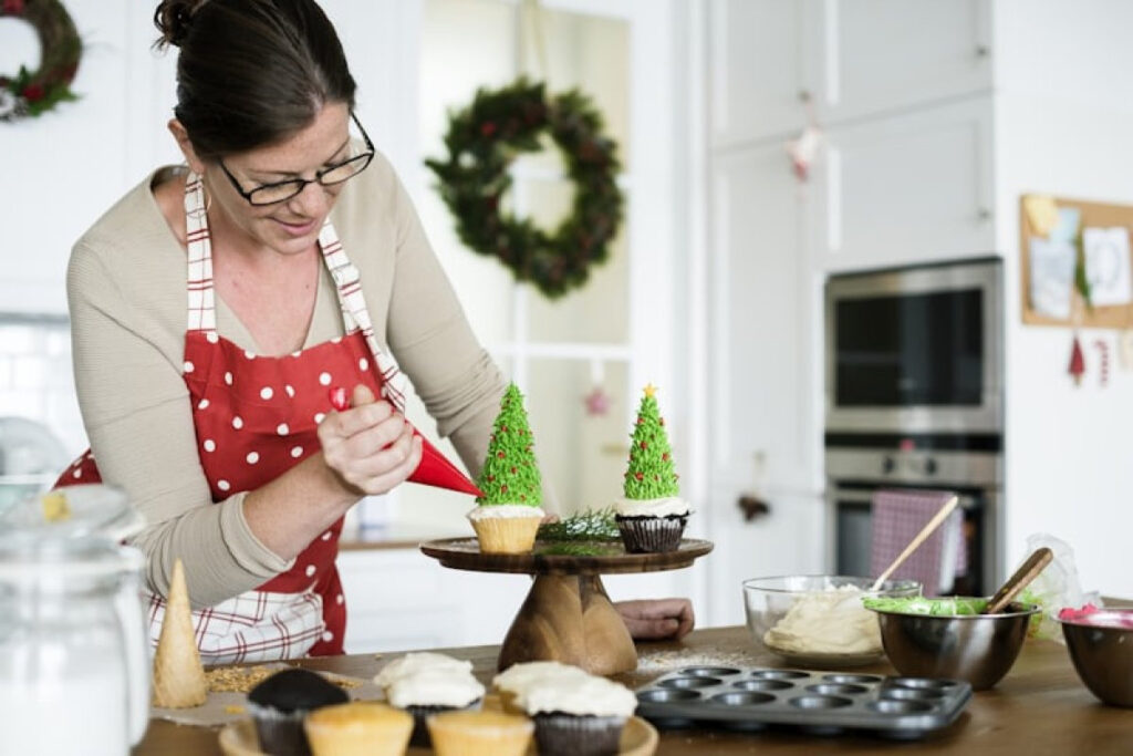 A picture showing a woman decorating a cupcake for celebrating Christmas on a budget.
