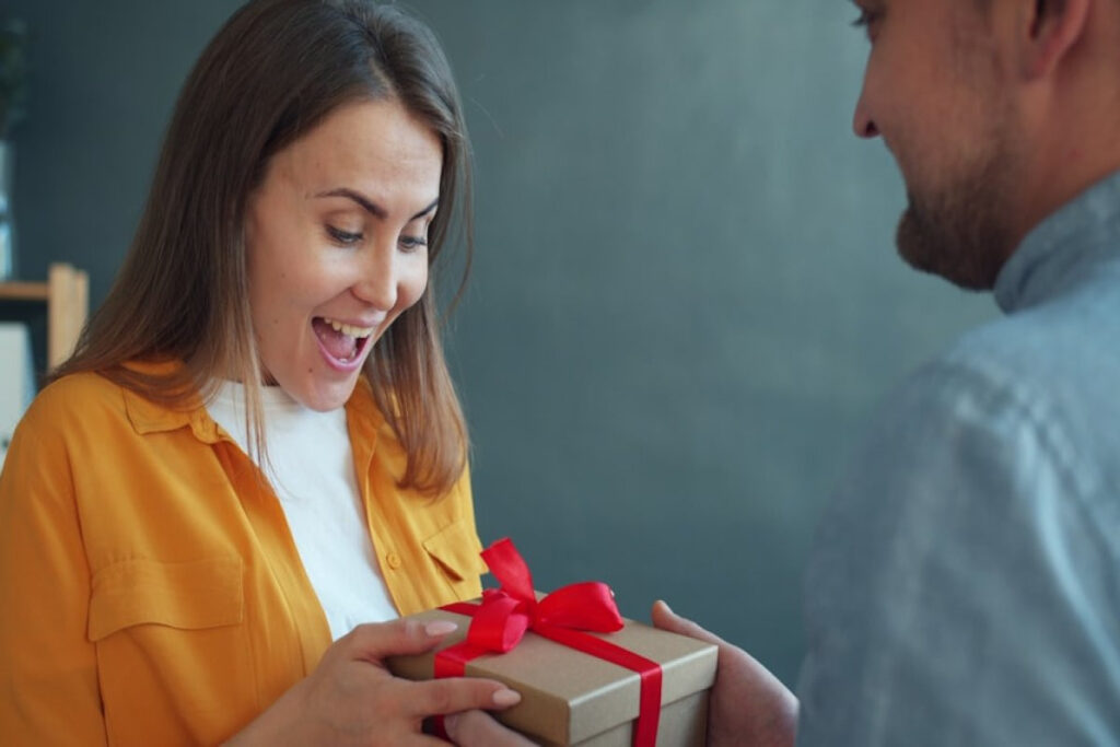 A picture showing a woman happily receiving a gift from a man.