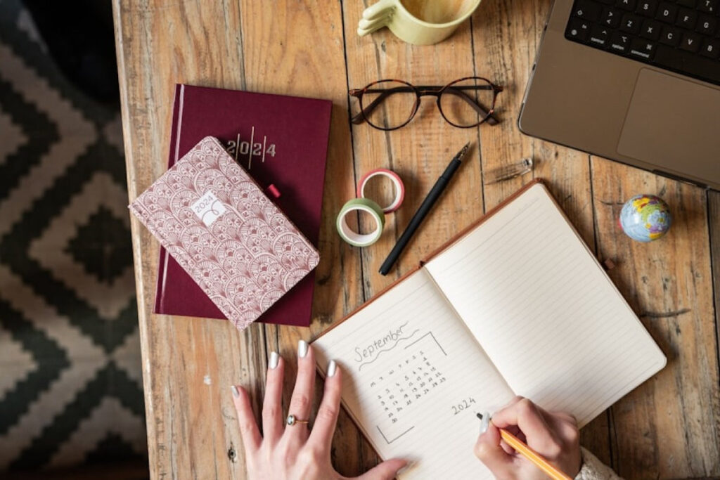 A picture showing a person sitting at a table with a notebook and pen, planning to save or pay off debt.
