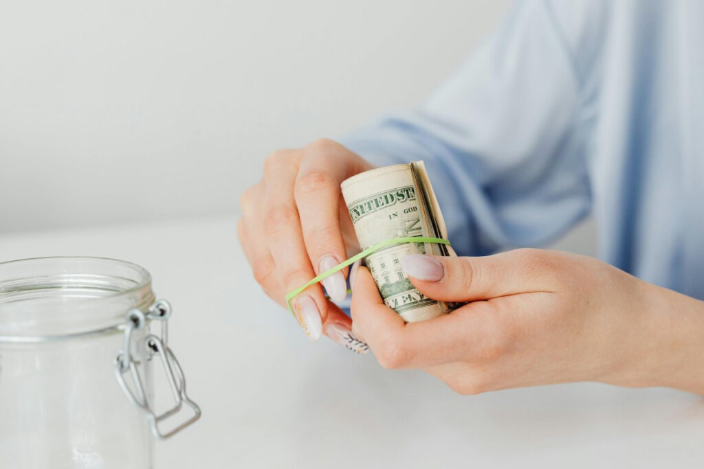 A picture showing a person tying paper money with a rubber band to save or pay off debt.