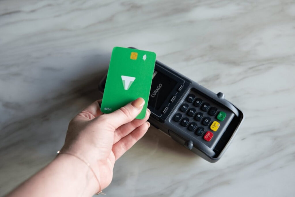 A person holding a green credit card next to a calculator