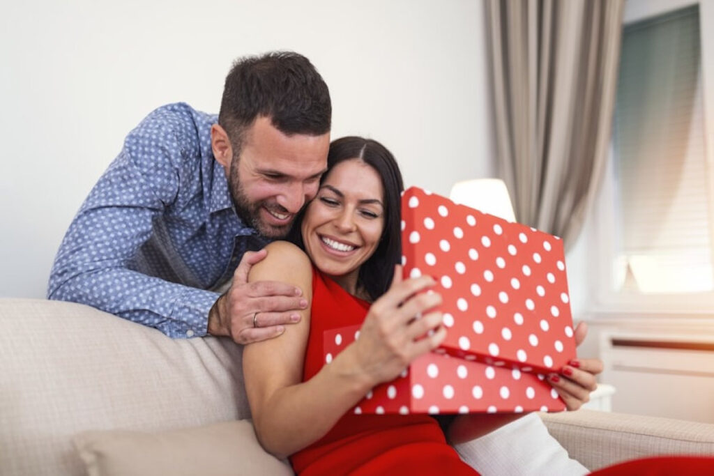 A picture showig a Man surprising his wife with Valentine's Day Gifts Under $50 gift box