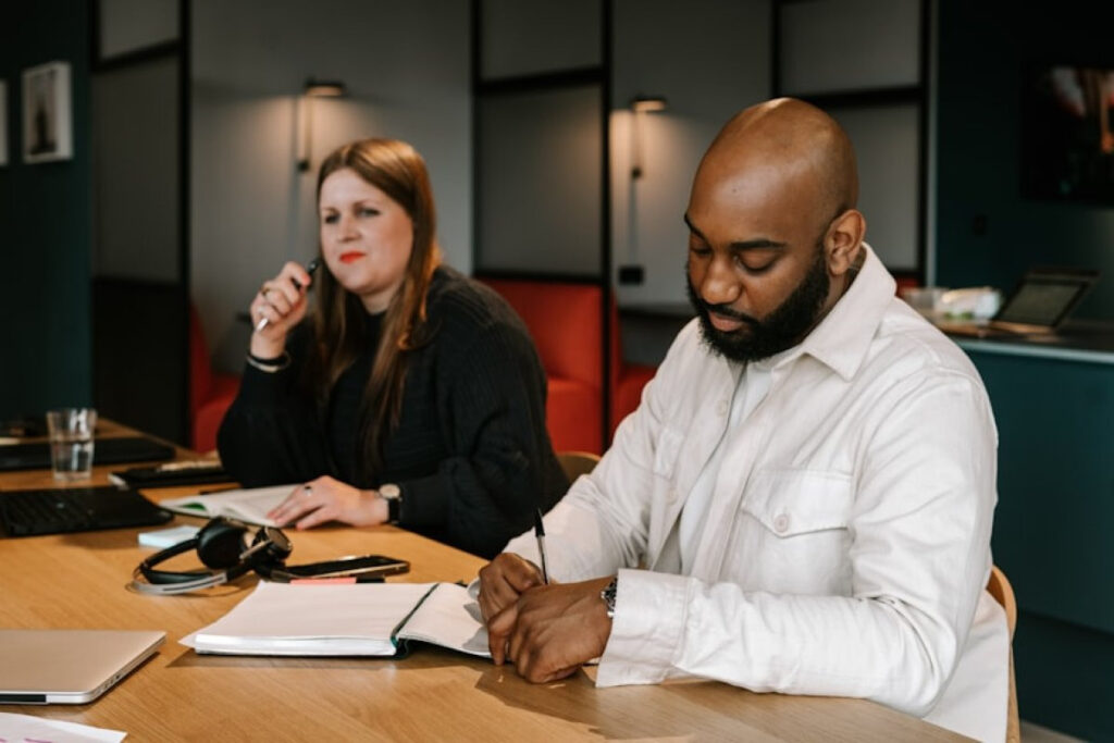 A picture showing a man and woman listing goals at a table, practicing Couples Financial Planning.