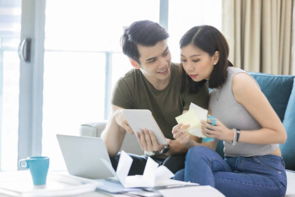 A picture showing a man and woman sit on a sofa, a representation of how to discuss money with your partner calmly and openly.