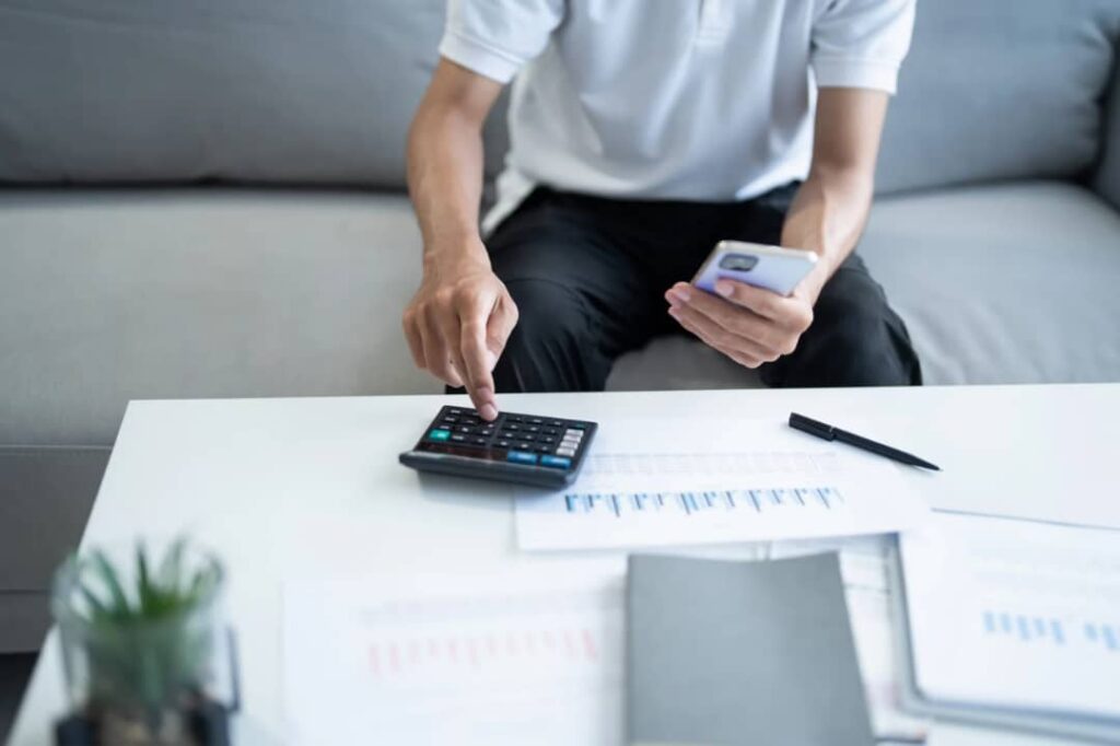 An image showing someone listing and calculating their expenses and income so they can manage money as a couple well