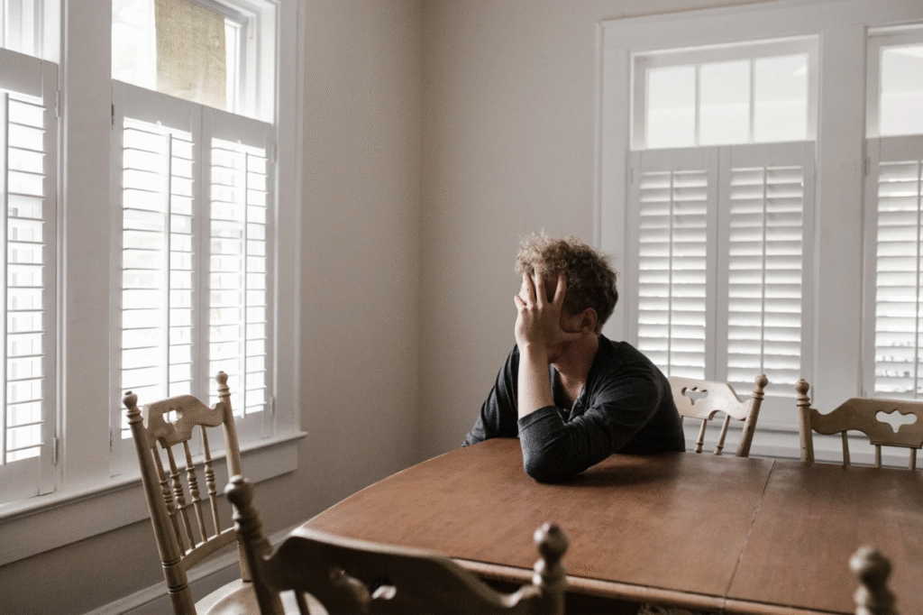 An image showing an exhausted man sitting by the window