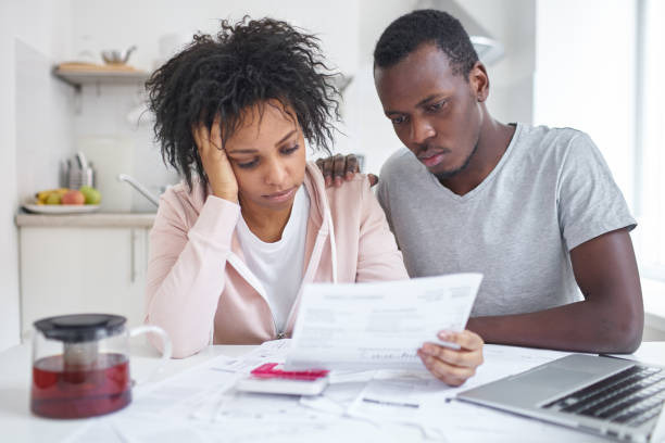 An image showing a stressed couple reviewing bills at home, showing financial strain and the impact of a financially irresponsible partner.