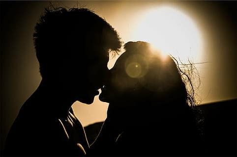 An image showing a romantic moment between a couple kissing in a dimly lit place