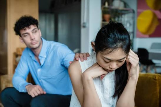 An image showing A man approaches his upset partner to understand the cause of her emotional state.