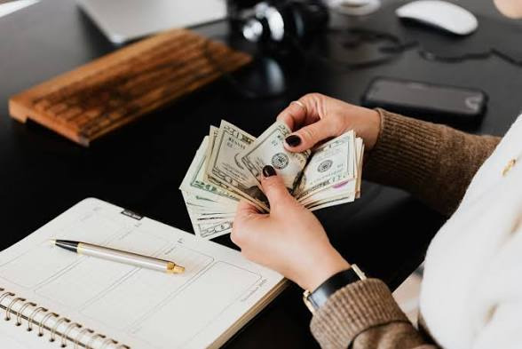 An image showing Hands counting cash on a desk, representing money management and financial habits in a relationship.