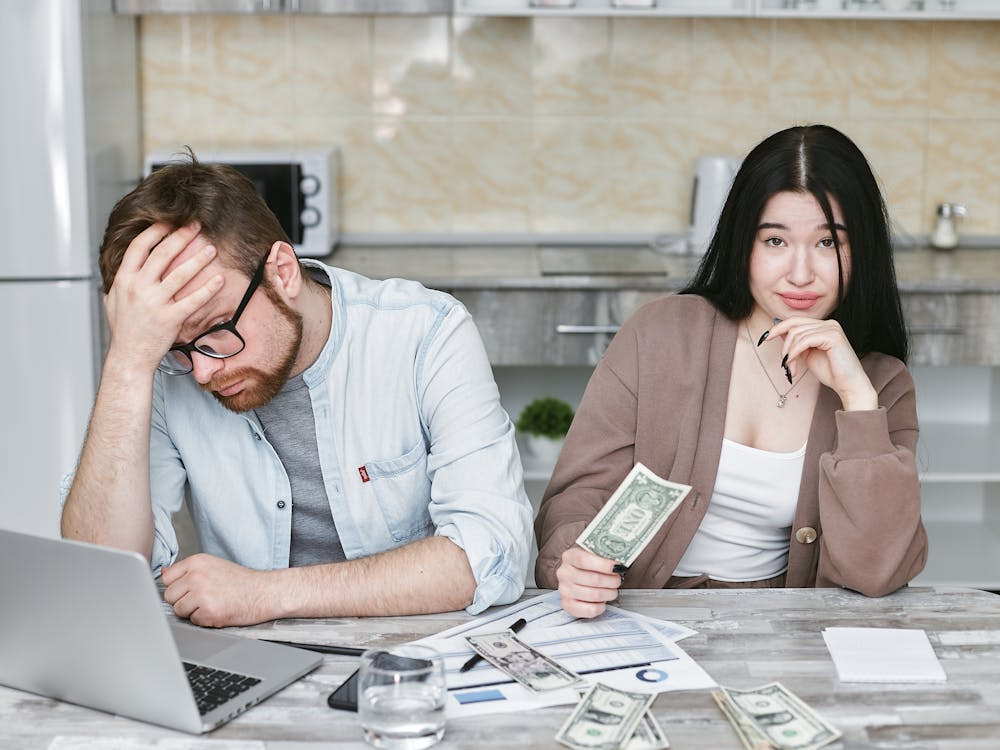 An image showing Stressed couple discussing bills and money problems, showing the impact of a financially irresponsible partner