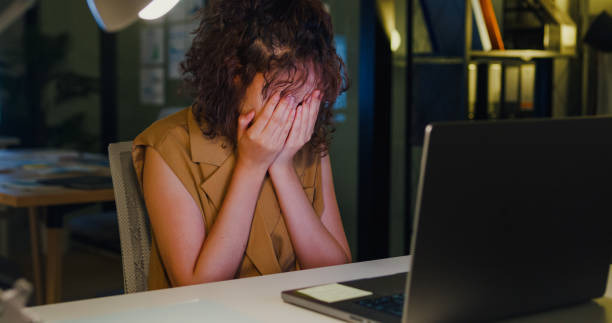 An image showing a stressed woman working late and worrying about finances during career change caused by a partner changing careers.