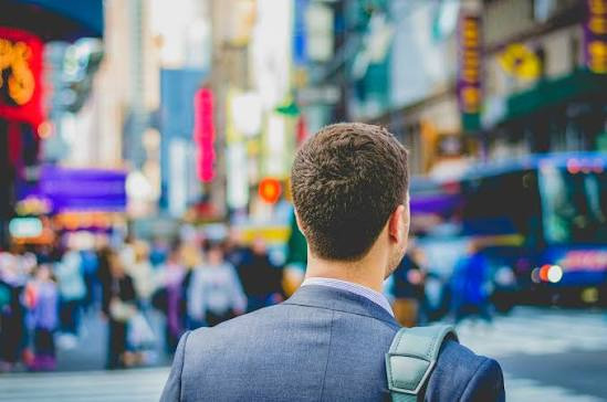 An image of a professional man walking through the city during a partner's career change while navigating uncertainty and planning a new career path.