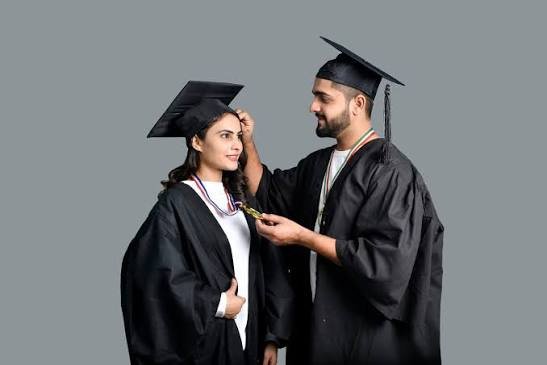 An image showing Two happy graduates in caps and gowns celebrating success after working together to pay off student loans as a couple and achieve financial freedom.