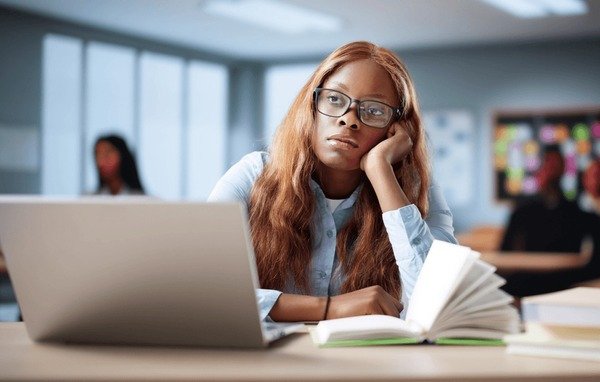 An image showing A bored female student staring at her laptop while studying, showing the emotional stress couples may face